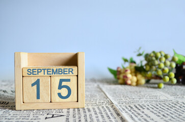 September 15, Calendar cover design with number cube with fruit on newspaper fabric and blue background.	