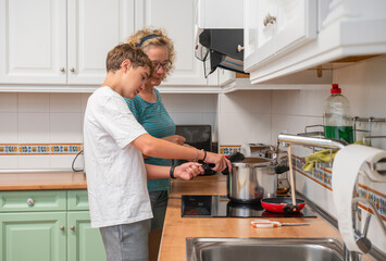Mother guiding her teenage son while using a pressure cooker in a home kitchen, sharing a careful and educational cooking moment that emphasizes safety and family bonding