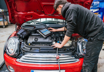 Mechanic diagnosing car engine problems using diagnostic software on tablet