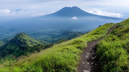 A green field is on Mount Merbabu in Indonesia. Mountains can be seen far away.
