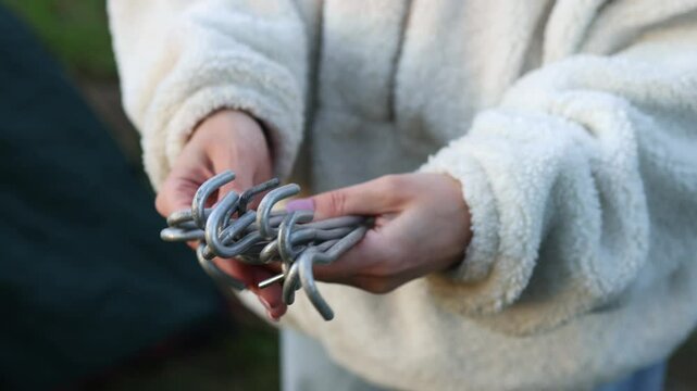 Female hands pull tent pegs out of a case. Close-up shot