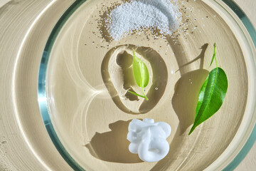 A swatch with textures of several skin care products in a petri dish on a beige background.