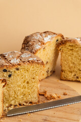 Panettone cake with raisins and candied fruit, sweet traditional Italian pastry on beige background. Easter cake or Christmas pastry cut in a half.