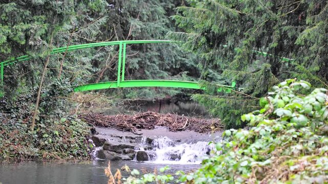 small waterfall in the woods with an old iron bridge in Winter. Fast flowing waterfall.