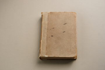 A vintage book with a worn brown cover and a taped spine, reflecting age, history, and the passage of time