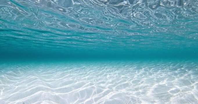 Transparent tropical sea underwater with white sand sea bottom and waves