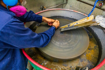 Worker Polishing Material on a Wet Grinding Machine in Workshop