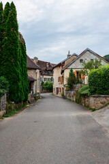 A peaceful and narrow street lined with traditional stone houses in the village of Mouthier-Haute-Pierre, along the Via Francigena in eastern France.