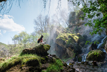 Young woman standing in front of a spring waterfall