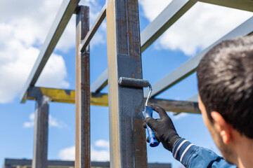Man painting metal poles. Selective focus.