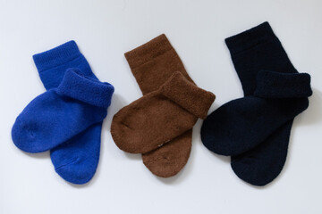 Three pairs of warm socks on a white background, blue, brown, black