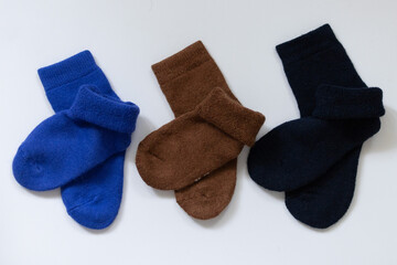 Three pairs of warm socks on a white background, blue, brown, black