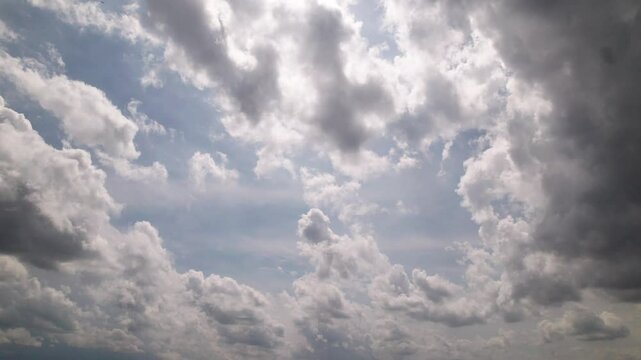 Panoramic view from sky looking and moving towards blue and white fluffy sky and storm precipitation forming before rain with bright sunlight weather leaking through steamy cumulus cloudscape