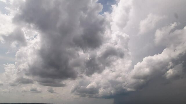 Panoramic view from sky looking and moving towards blue and white fluffy sky and storm precipitation forming before rain with bright sunlight weather leaking through steamy cumulus cloudscape