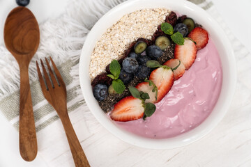 Presented by fruits putting yogurt toppings with strawberry, berry, oats, raisins and chia seed decorated by peppermint in white blow. Pink background. Set of healthy dairy product choice. Pecuniary.