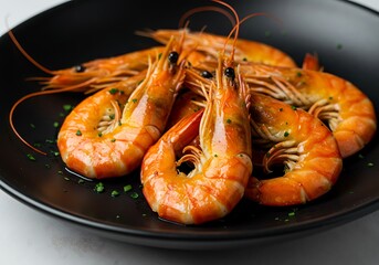 A black plate with a pile of cooked shrimp garnished with herbs on a white surface in a close up view