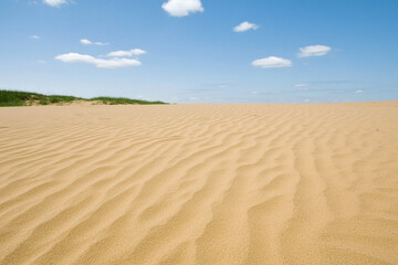 Naklejka premium Mirage appearing in a hot desert landscape with rippling sand and scattered clouds overhead