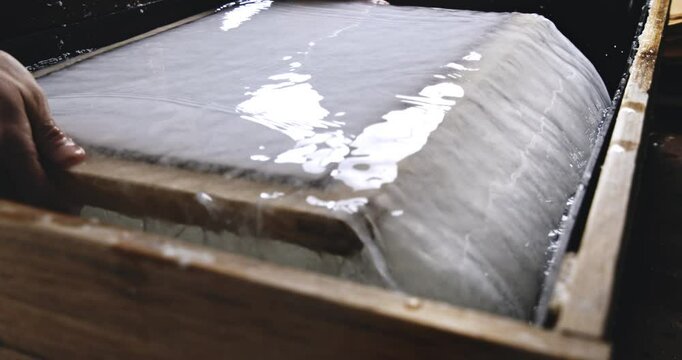 Super Slow Motion Close Up of Removing Sheets of Handmade Paper from Water Vat During Traditional Papermaking Process in Artisan Workshop with Natural Fibers and Wooden Tools at 1000 fps.