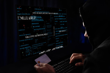 Criminal anonymous male approaching credit card of personal information database for codding encryption scam program in privacy system at night time at blue neon light room with server drive. Surmise.