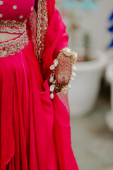 Woman in vibrant pink dress with traditional henna and shell jewelry. Cultural attire on display....