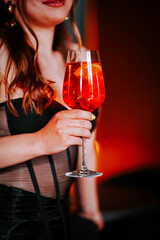 Woman holds a vibrant cocktail in an elegant setting during a nightlife experience