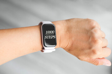 Smartwatch on wrist showing 10000 steps achieved on the screen, symbol of daily fitness goal and active lifestyle, concept of health