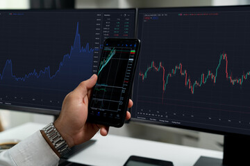 Trader businessman searching on smartphone, analyzing in dynamic stock exchange investment screen...