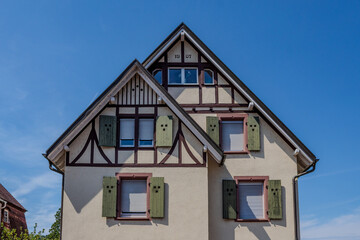 An old house with green windows and a unique design against a blue sky.