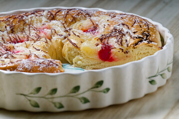 Delicious round glazed or easter bread cake with cherries, coconut and chocolate drizzle being partially eaten