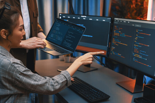 Serious of IT developers discussing intelligent website development coder system running data online two screens with laptop showing information network at neon light room at modern office. Infobahn.