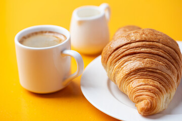 Croissant, espresso coffee and saucer with cream on yellow background. Cafe breakfast concept