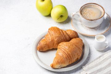 Croissants, coffee and green apples on grey background. Copy space