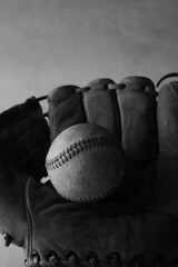Old used vintage baseball and glove still life, vertical view in black and white for sports background.