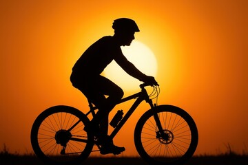Fototapeta premium A silhouette of a cyclist against a bright orange sunshine