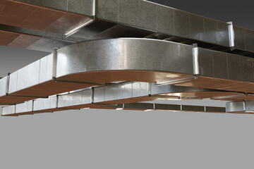 Modern HVAC air ducts with multiple curves and joints suspended from the ceiling, part of...