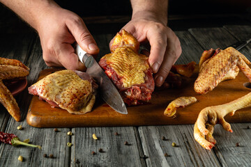 A chef skillfully cuts raw poultry on a wooden cutting board in a cozy kitchen. Surrounding ingredients hint at a flavorful meal in preparation