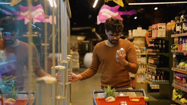 Arab man choosing fizzy drinks from fridge in store