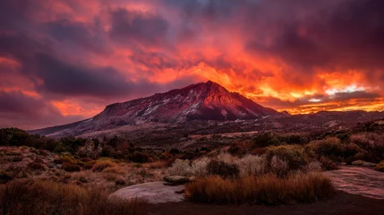 Gardinen A majestic mountain peak stands tall against a fiery sunset, its snow-dusted slopes illuminated by vibrant oranges and reds in the dramatic twilight sky at dusk. © MasTPX