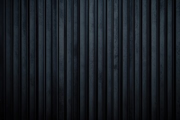 Obraz premium Dark, vertical metal slats form a textured facade. Close-up view of industrial, ridged panels. Dimly lit, heavy-duty structure