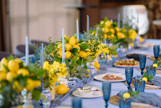Beautiful lemon centerpiece with blue glassware and candles creates a fresh, festive table atmosphere.