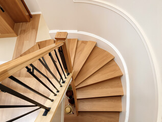 Fototapeta premium modern curved wooden staircase with a sleek black metal railing in a contemporary interior setting