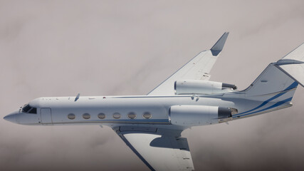 Side view of a Gulfstream IV (business jet) over  cloud layers, in beautiful light
