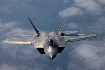Frontal view of a a F-22 Raptor  flying over the Pacific ocean and a cloud layer 