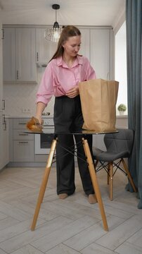 Woman unpacking groceries at home after shopping in supermarket buying food. Satisfied young online marketplace shopper unpacking a box of products ordered online with courier delivery vertical video