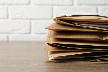 Post office. Stack of different paper envelopes on wooden table, closeup. Space for text