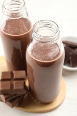 Tasty chocolate milk and pieces on white table, closeup