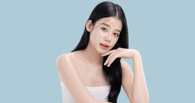 Glowing skin make up style of beautiful young Asian model isolated on blue background.
