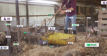 male farmer using shovel in poultry barn adding motion social media marketing icons swirling around - Powered by Adobe