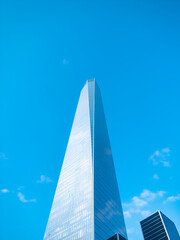 A gleaming glass skyscraper pierces a vibrant, cloudless blue sky, soaring, modern