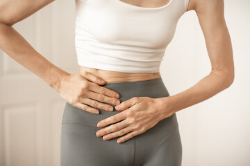 Young woman suffering from abdominal pain stomach cramps on light background. Gynecology concept
